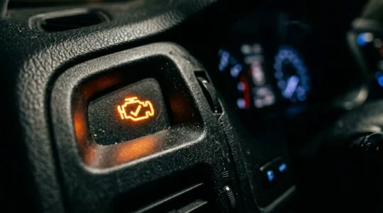 Gros plan sur un tableau de bord automobile moderne avec voyant moteur orange allumé, atmosphere inquiétante mais réaliste
