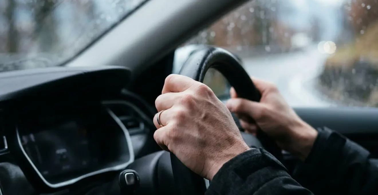 Vue rapprochée de mains sur un volant de voiture illustrant la maîtrise du véhicule en conditions d'aquaplaning
