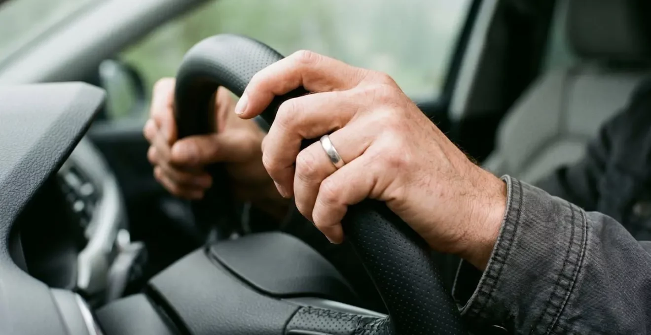 Gros plan sur les mains d'un conducteur sur le volant, avec une expression de concentration intense, évoquant la charge cognitive invisible