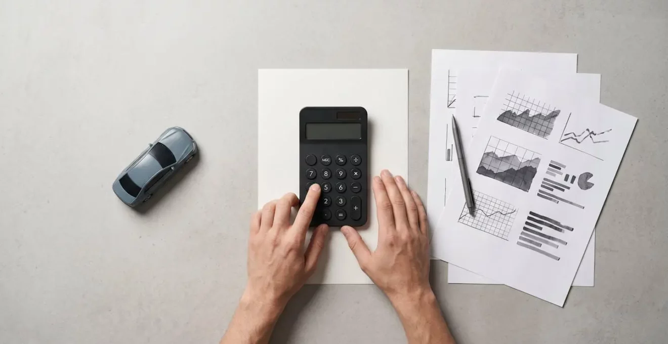 Mains d'une personne consultant une calculatrice et des documents financiers sur un bureau epure