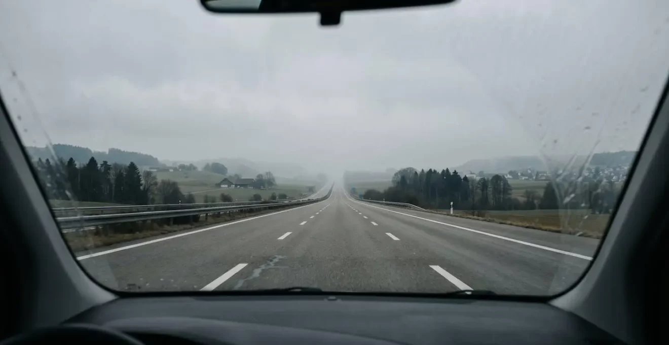 Vue à travers un pare-brise sur une autoroute suisse monotone s'étendant à l'infini