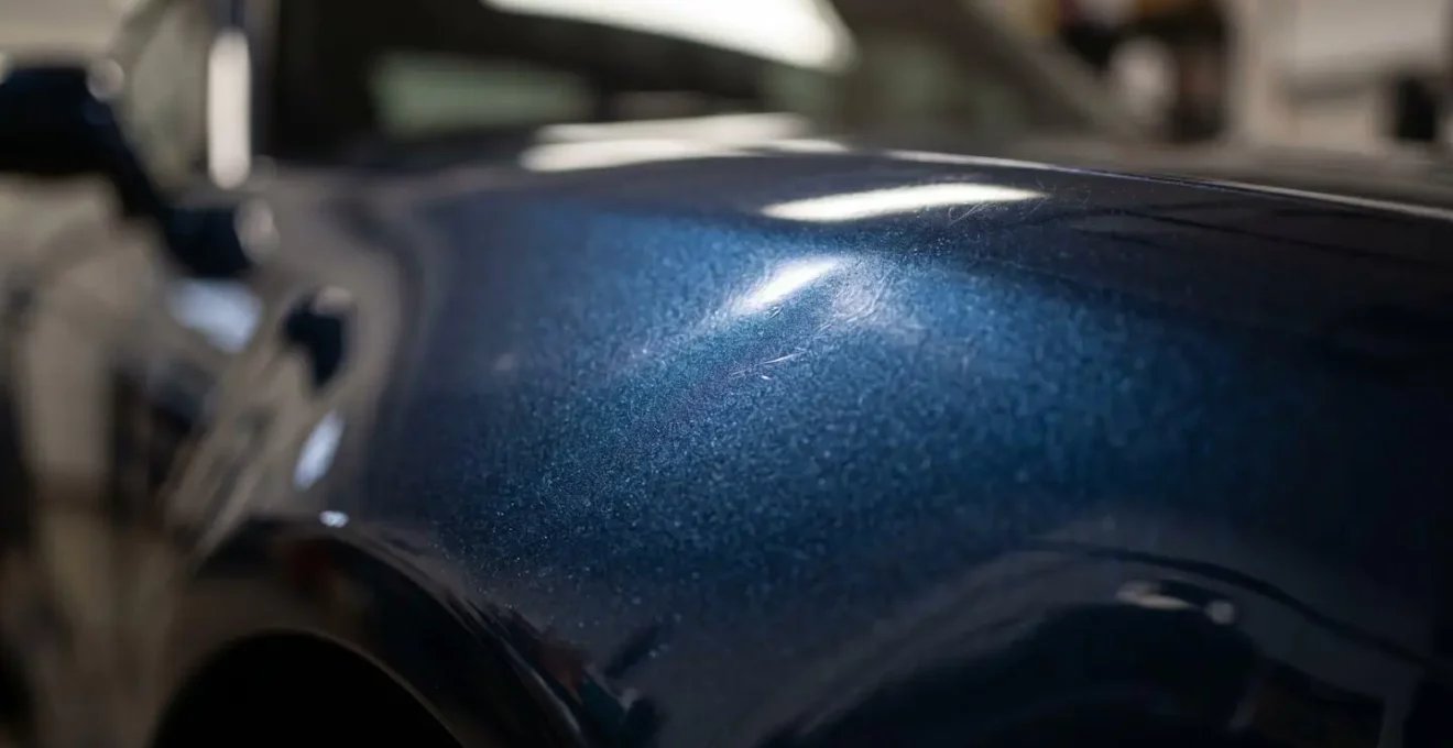 Gros plan macro sur les détails d'une carrosserie de voiture révélant textures et micro-rayures sous éclairage contrôlé
