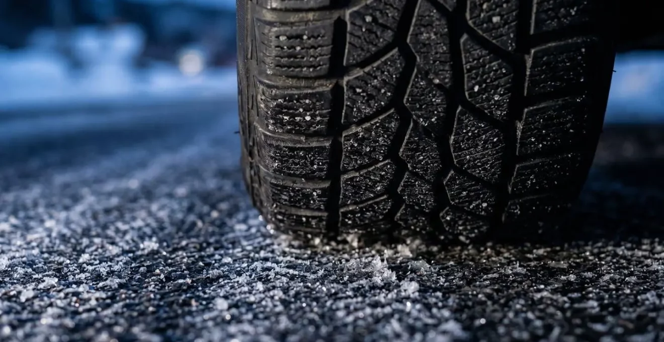 Gros plan sur des pneus hiver sur route enneigée, évoquant l'adhérence et la maîtrise du véhicule en conditions difficiles